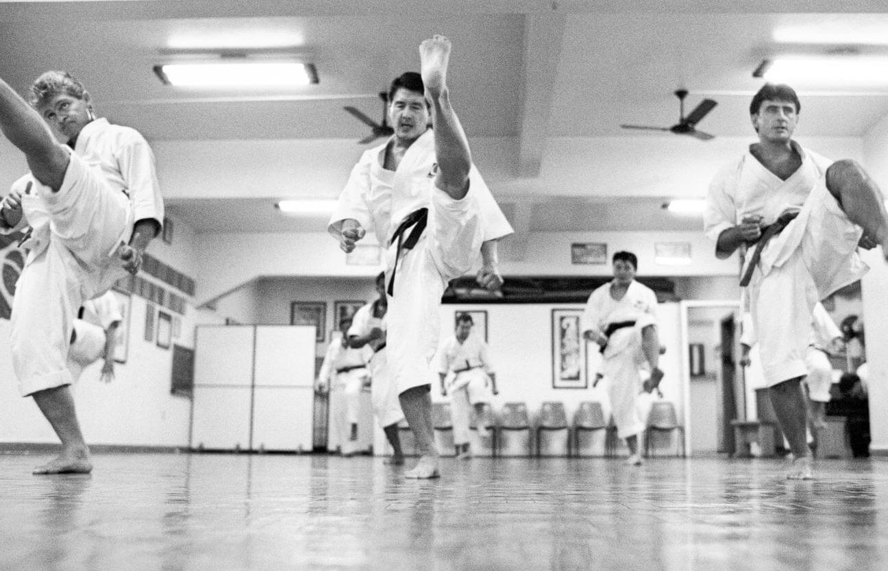 Professor Okuda mais jovem, treinando  karatê (Inventado por um descendente de um samurai) com outros homens. 